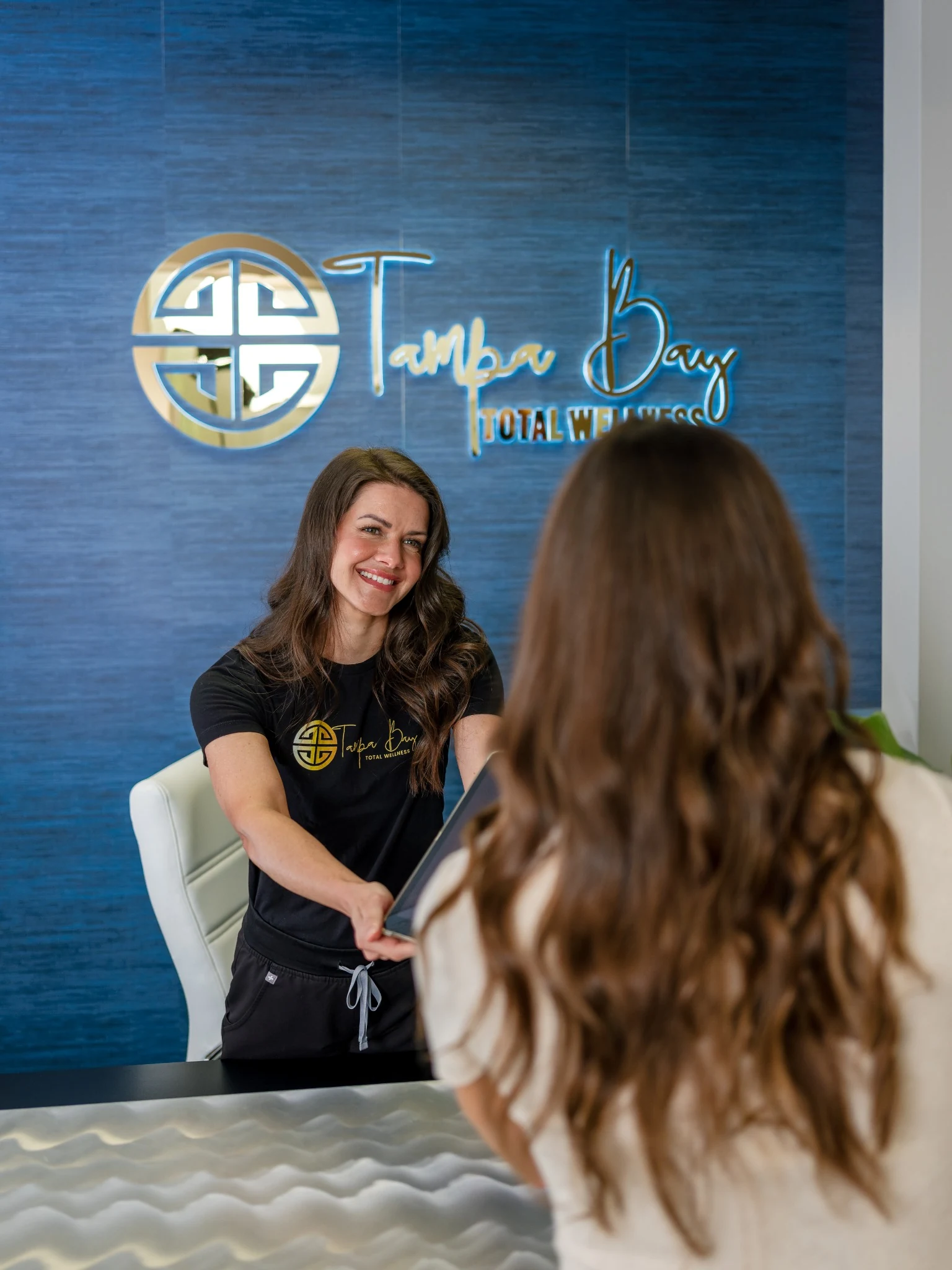 Patient checking in at Tampa Bay Total Wellness while learning about the Beauty Bank membership program.