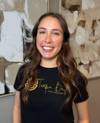 Smiling Tampa Bay Total Wellness team member wearing branded shirt indoors